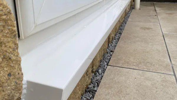 Newly fitted white UPVC external sill beneath a repaired window